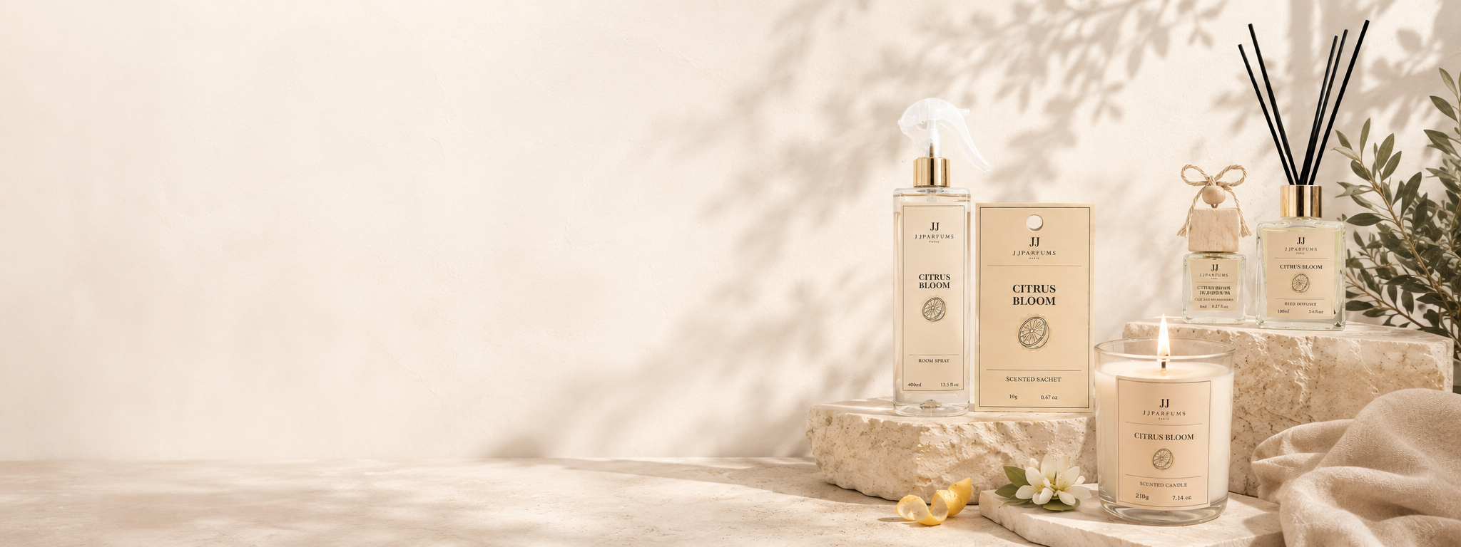 J&J Parfums Citrus Bloom collection banner with candle, room spray and reed diffuser on stone ledge